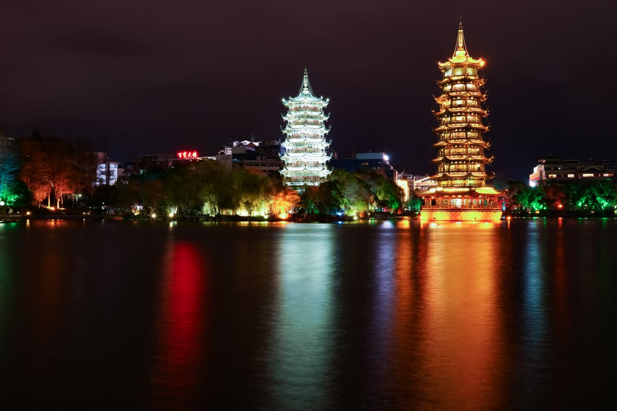 The Sun and Moon Pagodas illuminated at night, reflecting in the river near central Guilin's Two Rivers and Four Lakes waterfront where many hotels cluster