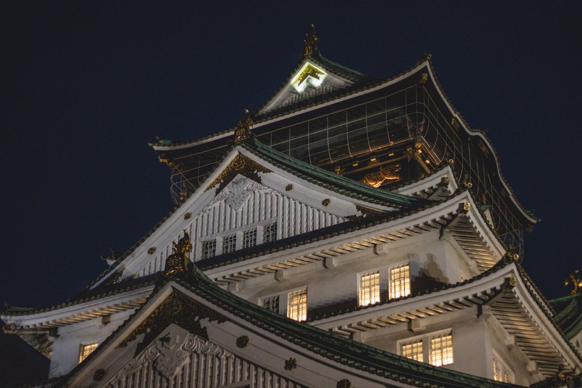 Osaka Castle illuminated at night against the dark sky