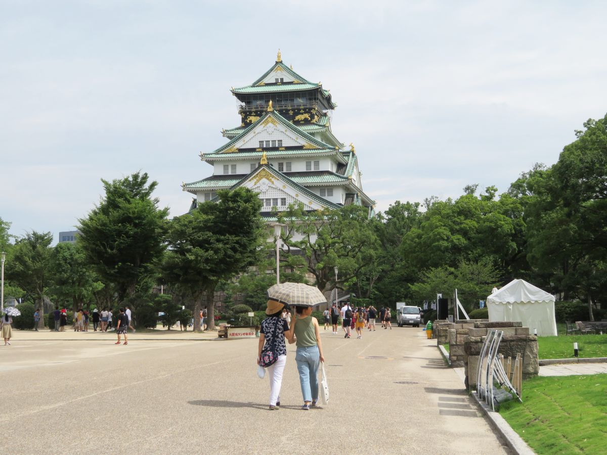 Visitors walking through Osaka Castle Park grounds toward the main tower
