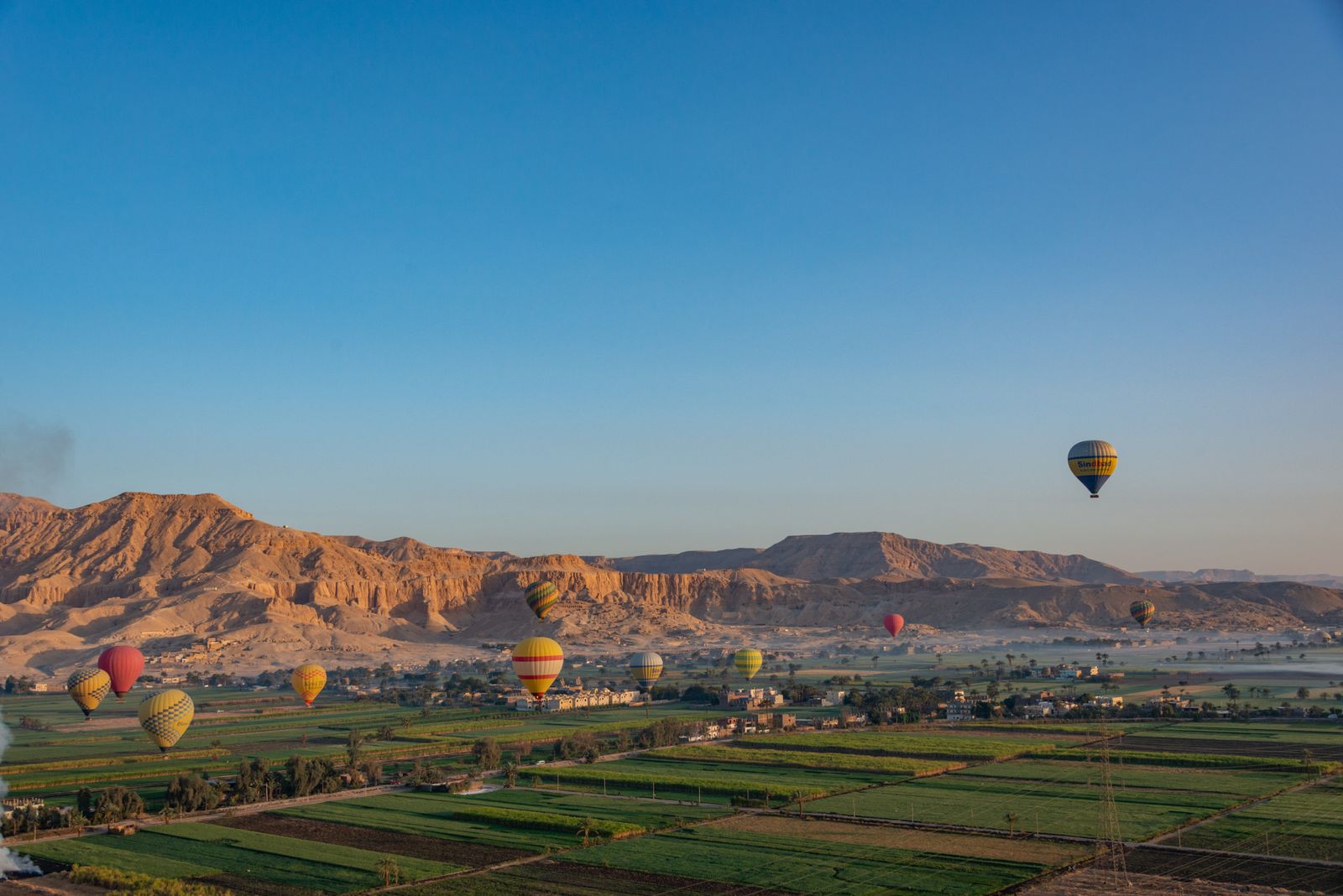 Colorful hot air balloons drifting over the Valley of the Kings at sunrise in Luxor, Egypt